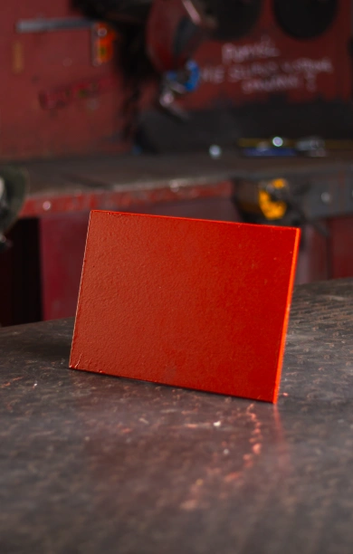 Red FLT steel beam positioned on a sleek black counter, emphasising its flat and sturdy design. The vibrant red finish highlights its durability and strength, making it suitable for various structural and construction applications. This FLT steel beam combines reliability and versatility for demanding projects.