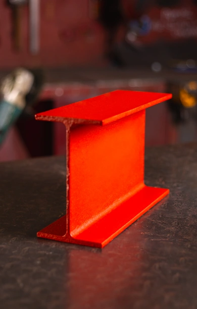 Red RSJ beam positioned on a black counter, showcasing its robust I-beam design. The bold red finish highlights its strength and durability, making it ideal for structural and load-bearing applications. This RSJ beam is a reliable choice for construction and engineering projects requiring stability and support.