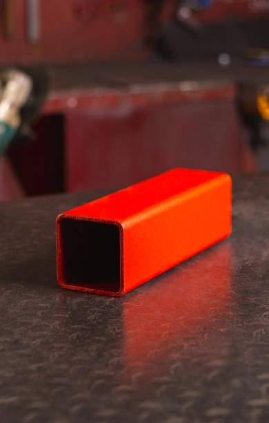 Red SHS steel beam positioned on a black counter, highlighting its square hollow section design. The vibrant red finish emphasises its strength and durability, making it a reliable choice for structural and construction projects. This SHS steel beam combines versatility and robust performance for various applications.